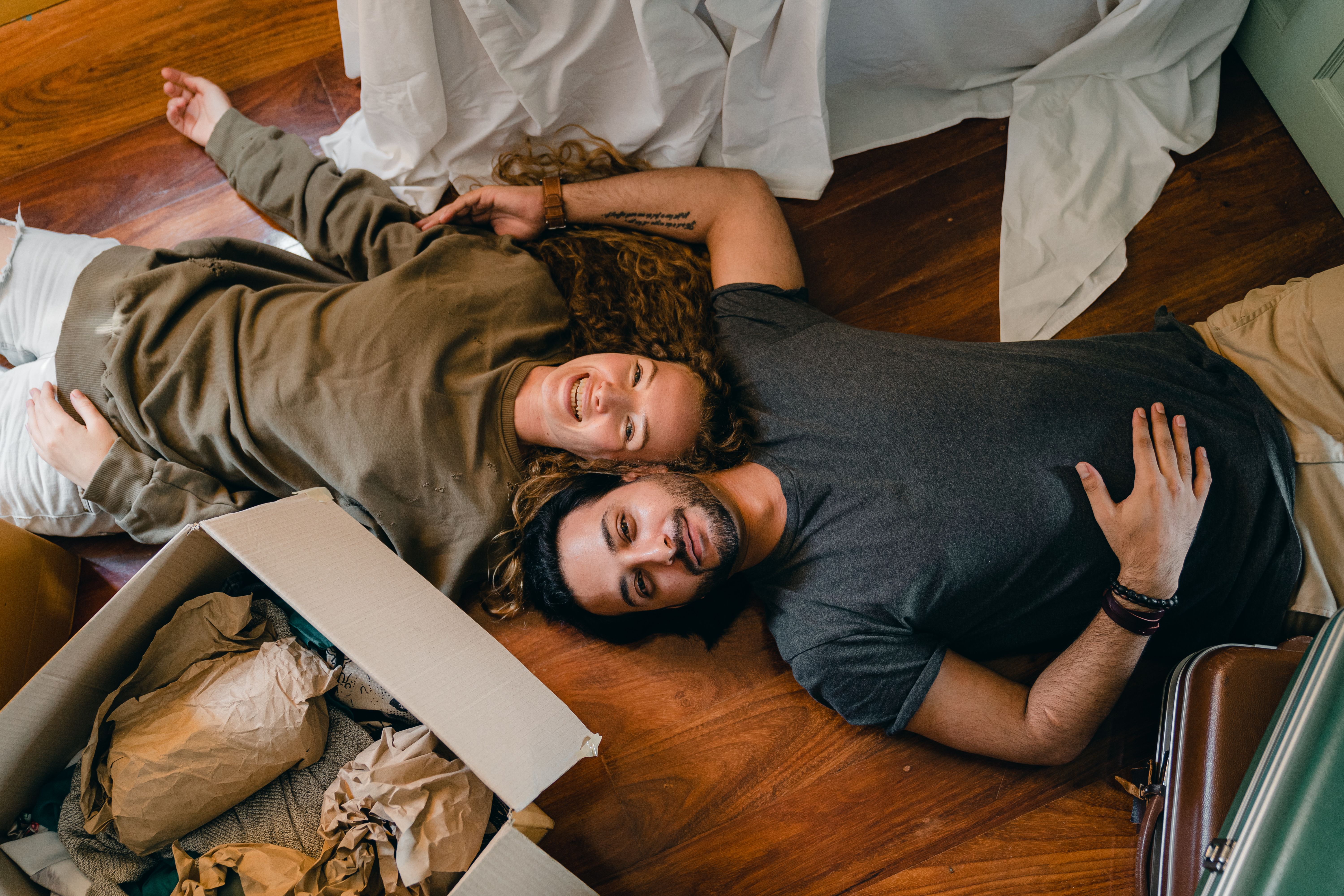 A couple lying on the floor of their new home, resting among boxes